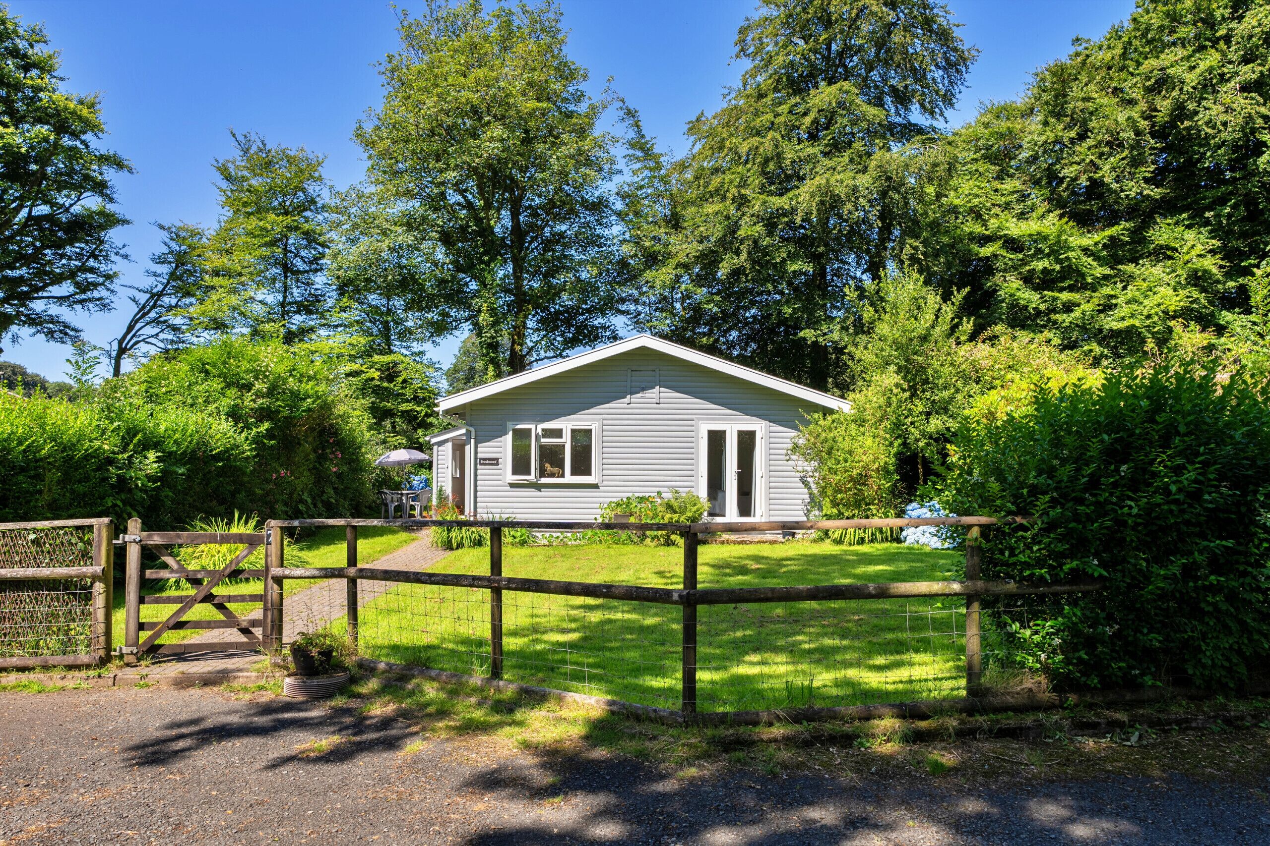 A single-story house with a fenced yard, surrounded by trees.