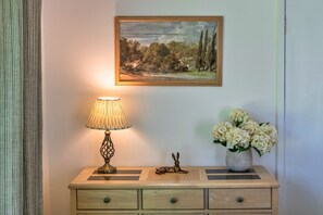 A bedside table with a lamp, a small sculpture, and a vase of flowers. - Brockwood (Bradworthy)