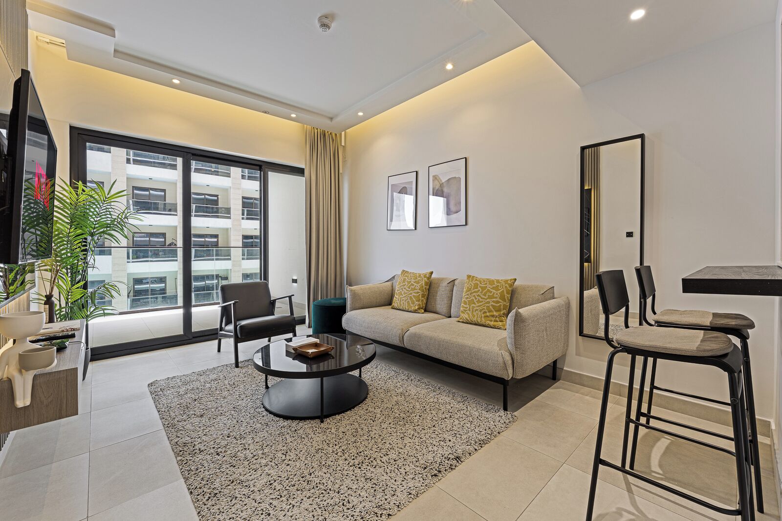 A modern living room with a sofa, armchairs, a coffee table, and a large window with a view of a building.