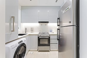 Eine moderne Küche mit Waschmaschine, Herd, Backofen und Kühlschrank.