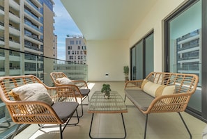Ein Balkon mit Korbmöbeln, einem kleinen Tisch und einem Blumentopf.