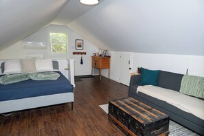 A bedroom with a bed, a dresser, a nightstand, a window, and a view of the outdoors.