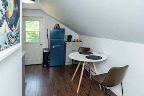 A small kitchen with a blue refrigerator, a coffee maker, and a dining table with two chairs.