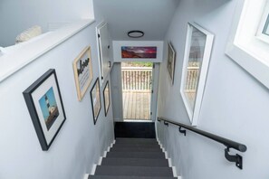 A stairway with framed pictures, a view of the outside, and a wooden deck.