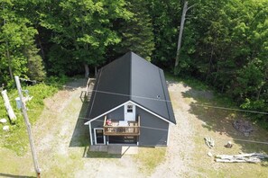 A single-story house with a dark roof, a front porch, and a small deck.