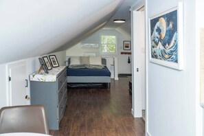 A bedroom with a bed, dresser, and artwork on the wall.