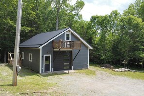 A two-story cabin with a balcony, a garage, and a front door.