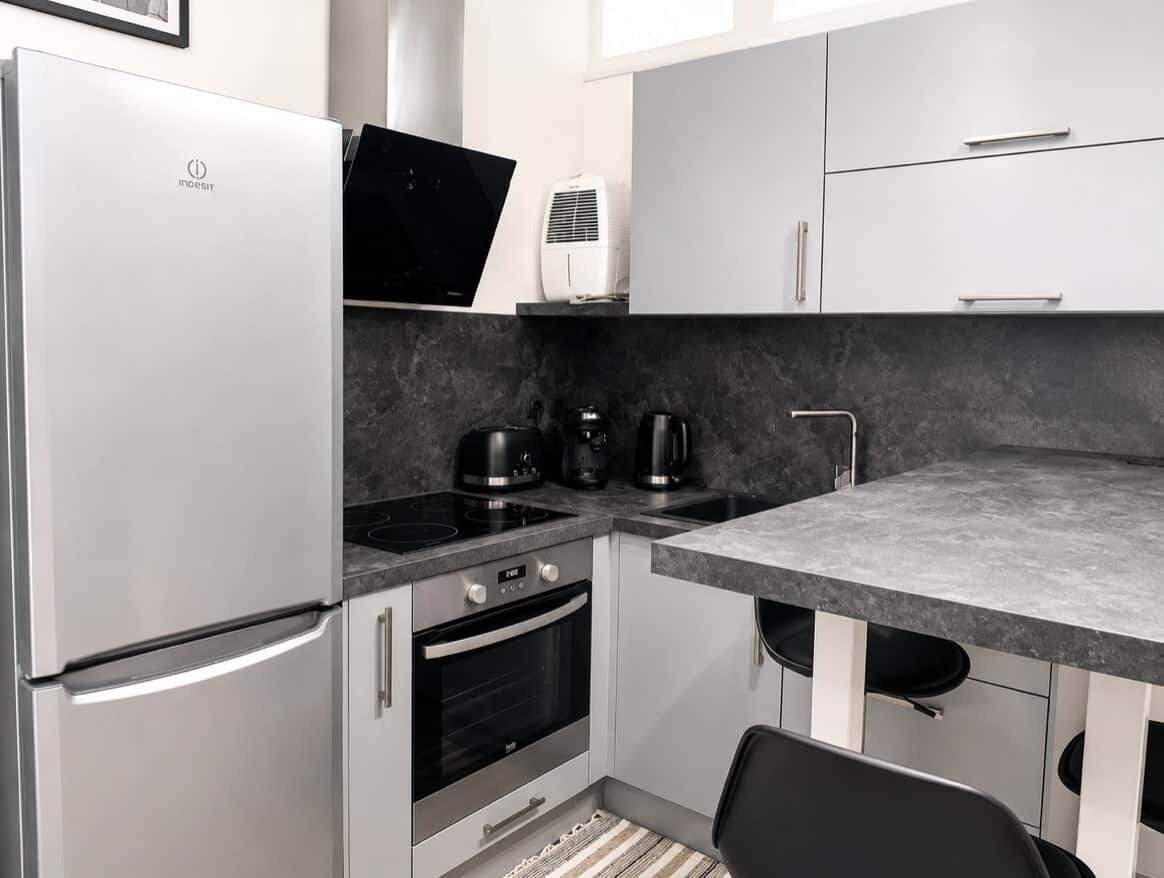 A modern kitchen with a refrigerator, oven, and coffee maker.