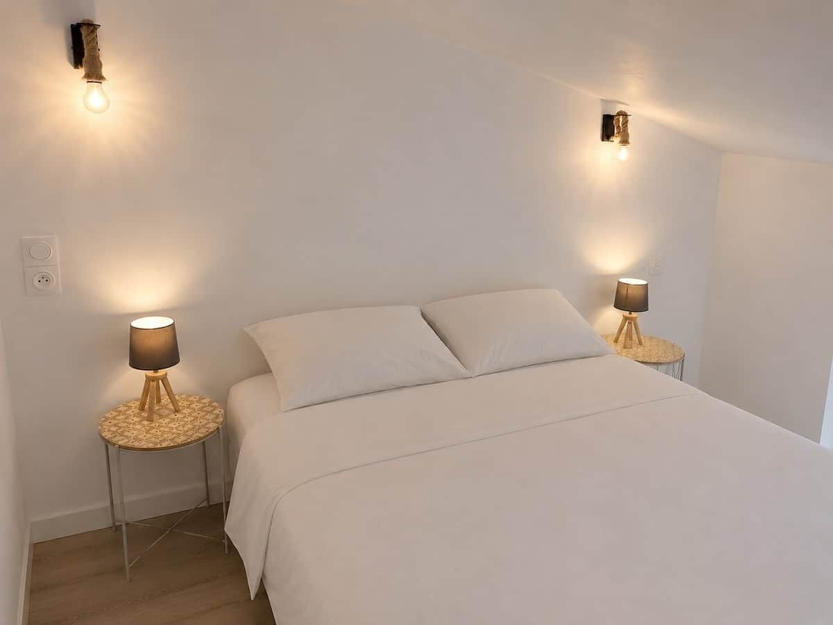 Une chambre à coucher avec un lit, deux tables de chevet avec des lampes et des appliques murales.
