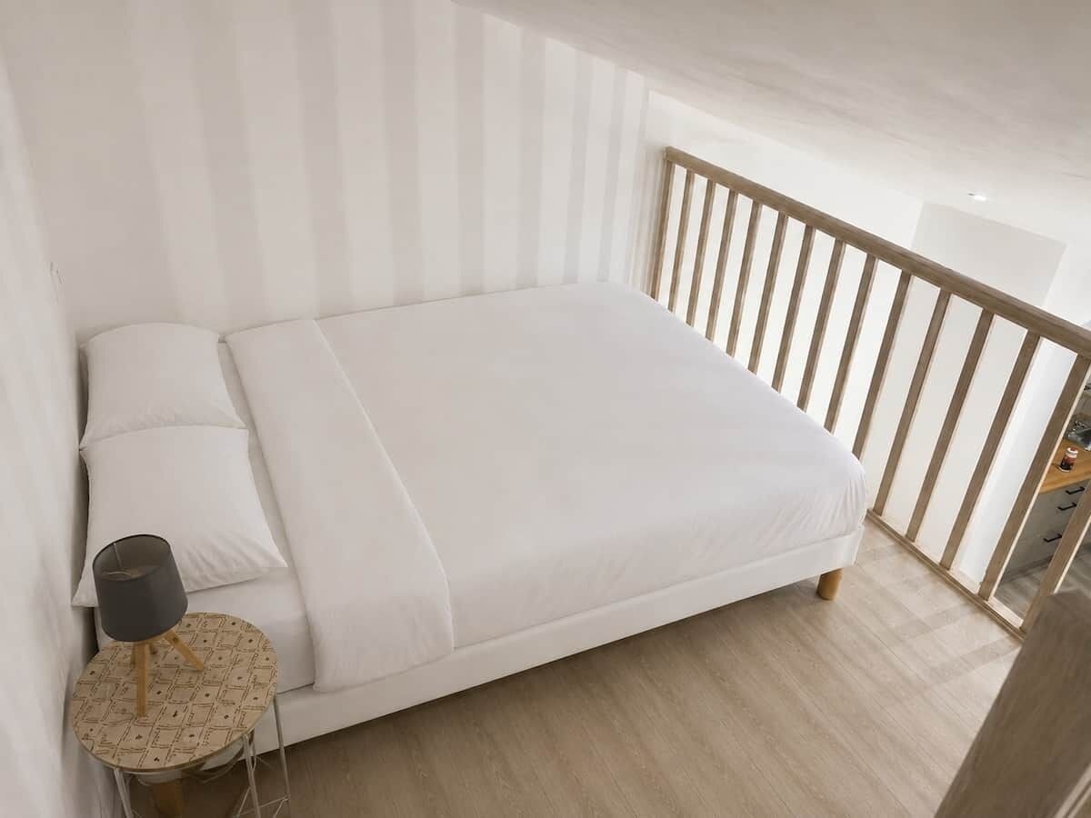 A modern bedroom with a large bed, a bedside lamp, and a view of the balcony.