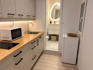Eine kleine Küche mit Mikrowelle, Spüle und Kühlschrank.