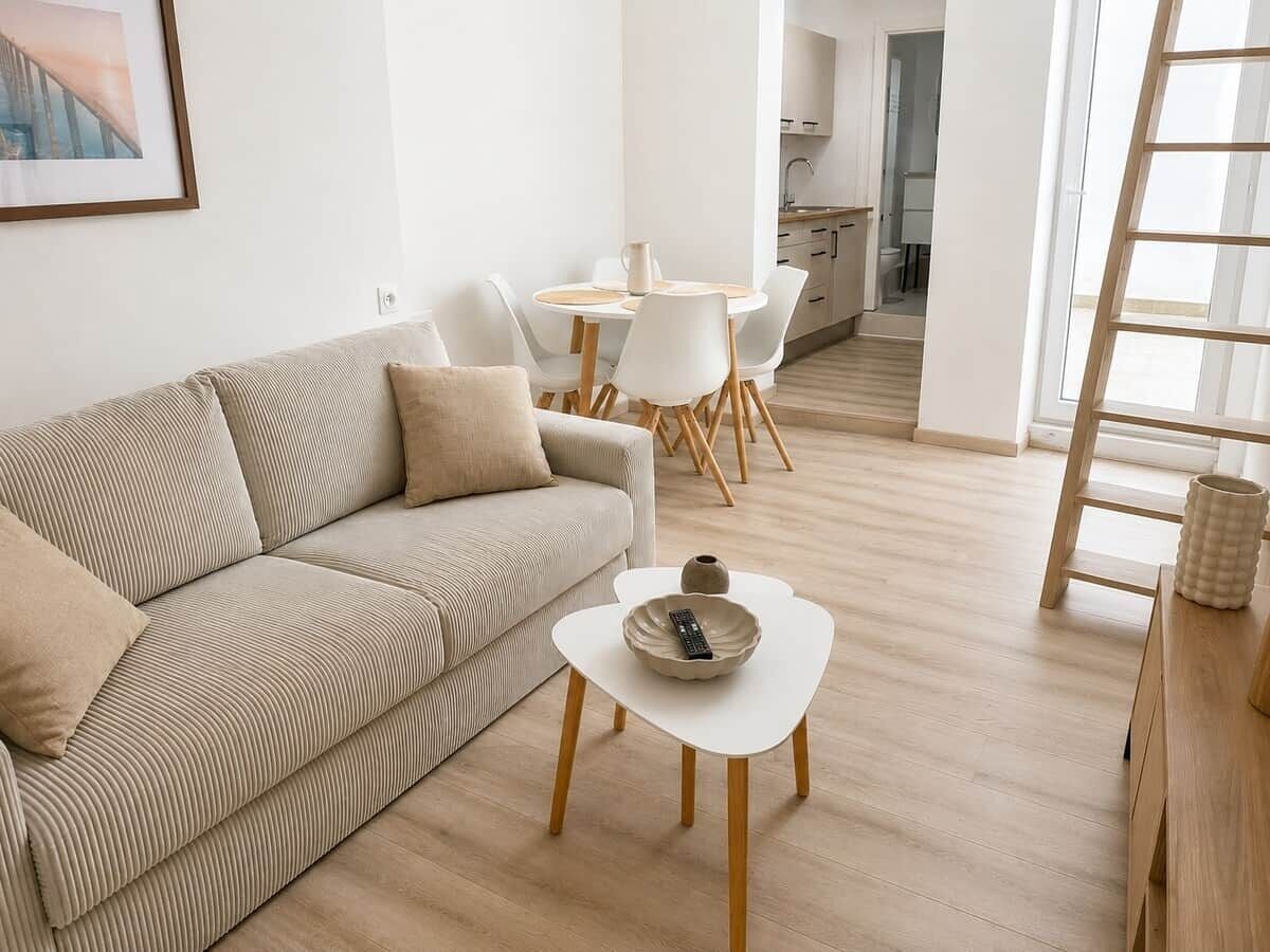 A modern living room with a sofa, a coffee table, and a dining area with chairs and a table.