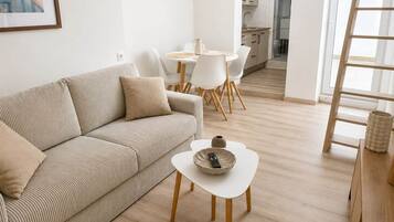 A modern living room with a sofa, a coffee table, and a dining area with chairs and a table.