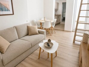 Ein modernes Wohnzimmer mit einer Couch, einem Couchtisch und einem Essbereich mit Stühlen und einem Tisch.