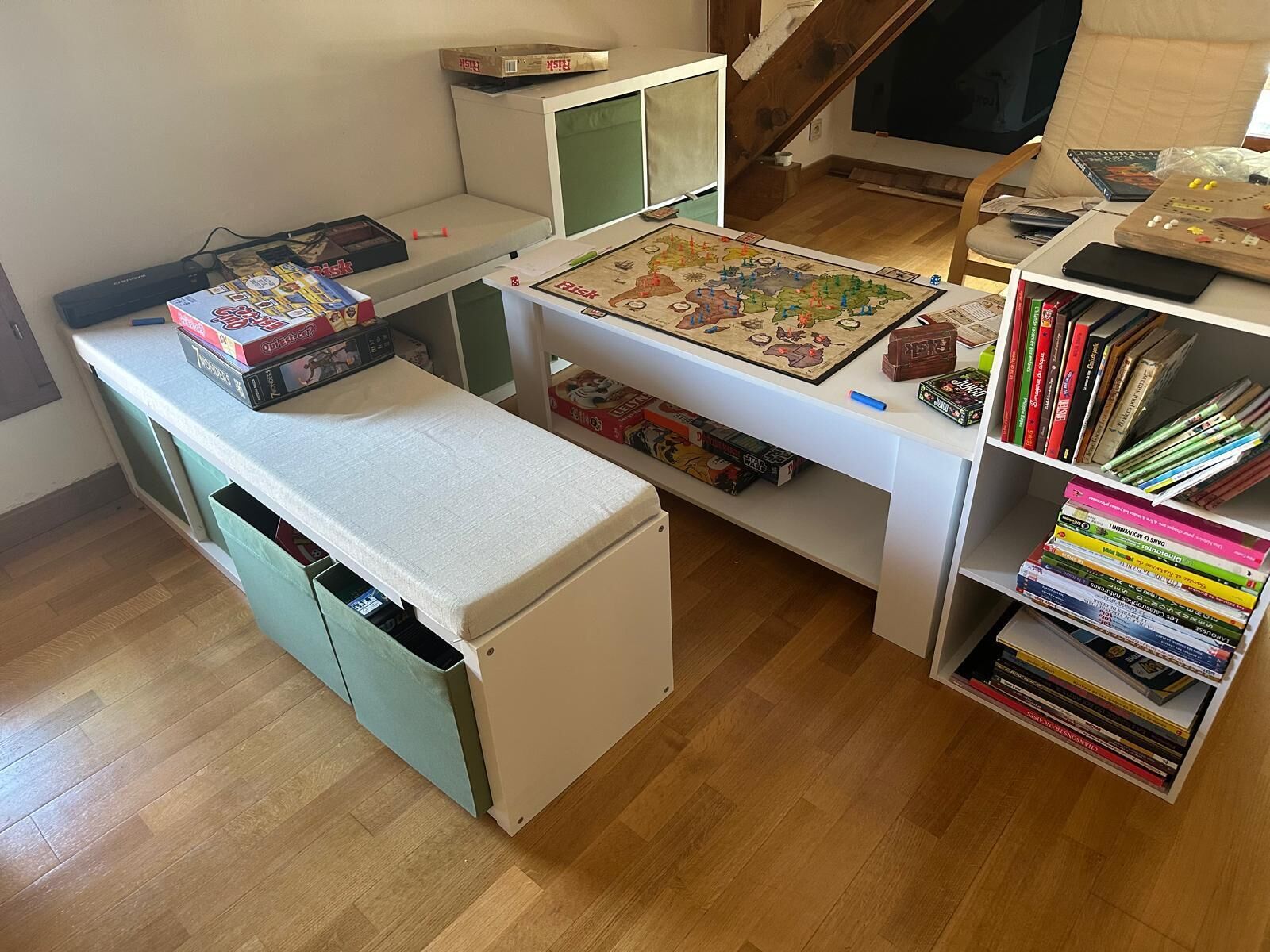 A room with a desk, a bookshelf, and a small table with board games.