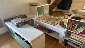Et værelse med et skrivebord, en reol og et lille bord med brætspil.