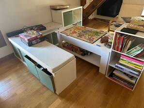 Ein Zimmer mit Schreibtisch, Bücherregal und einem kleinen Tisch mit Gesellschaftsspielen.
