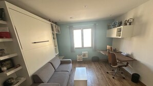 En kompakt opholdsstue med sofa, skrivebord og opbevaringsmøbler.