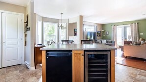 A kitchen with a built-in dishwasher, a dining area with a bench, and a living room with a sofa.