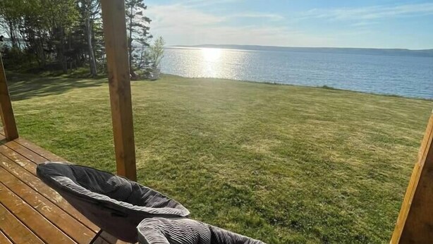 A wooden deck with a view of a lake and a grassy area.