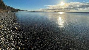 A calm lake with clear water reflecting the sky, surrounded by a rocky shoreline.