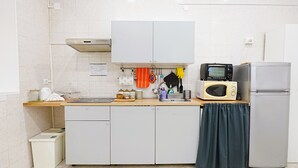 Eine Küche mit weißen Schränken, einer Mikrowelle, einem Kühlschrank und einem Spülbecken.