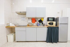Eine Küche mit weißen Schränken, einer Mikrowelle, einem Kühlschrank und einem Spülbecken.