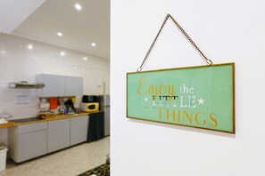 Une cuisine avec des armoires blanches, un plan de travail en bois et une enseigne suspendue sur laquelle on peut lire : « Savourez les petits plaisirs de la vie. »
