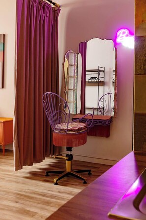 Een kamer met een paarse stoel, een spiegel en een houten vloer.