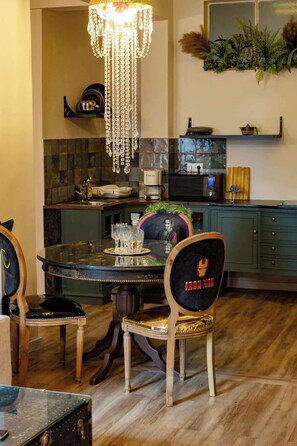A dining area with a chandelier, a round table, and chairs with a superhero-themed backrest. - Monastiraki Art House (Athina)