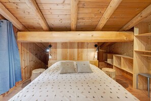 Habitación de cabaña de madera con cama, dos lámparas de noche y una estantería de madera.