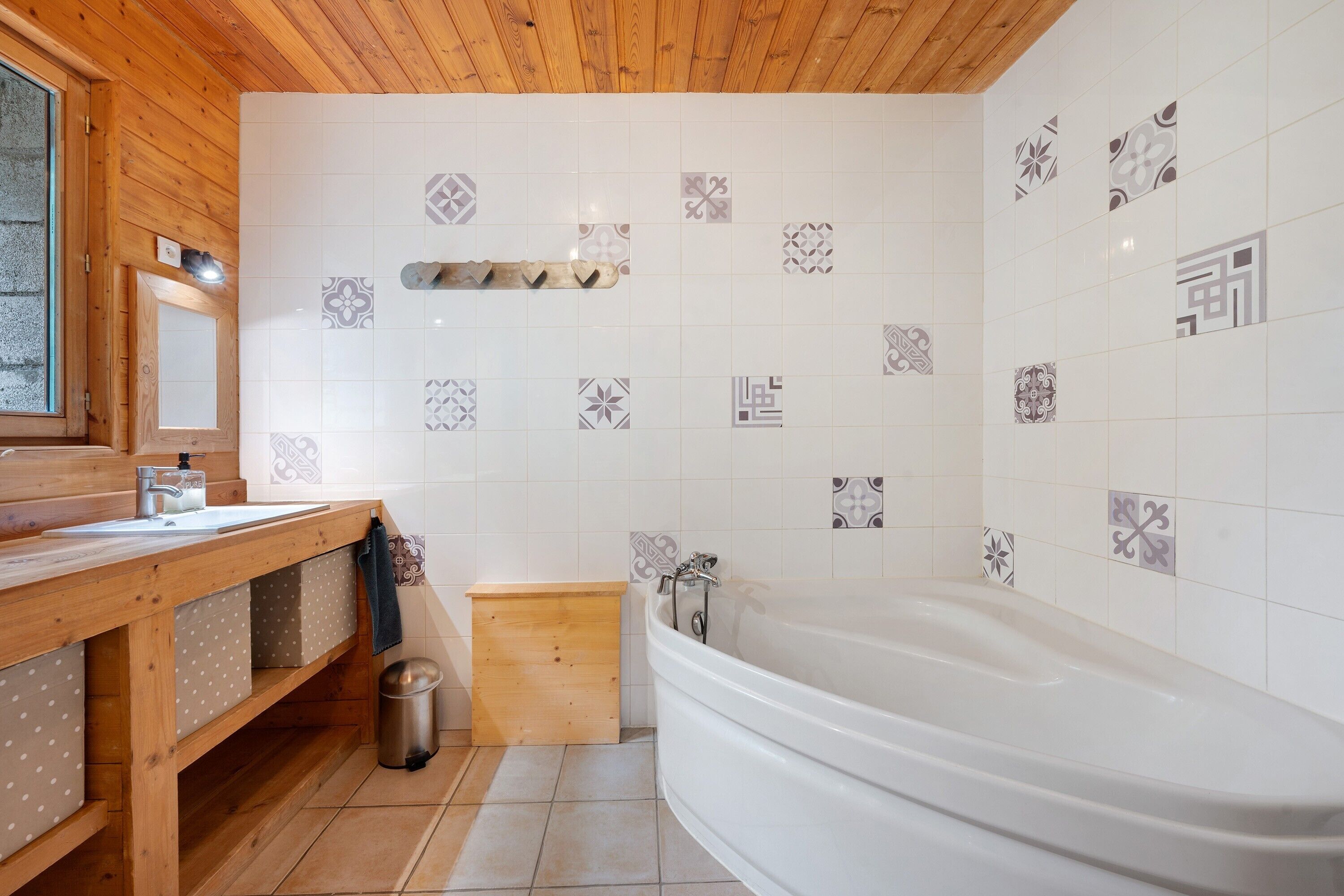 Un baño con tocador de madera, lavamanos, espejo, inodoro y bañera.