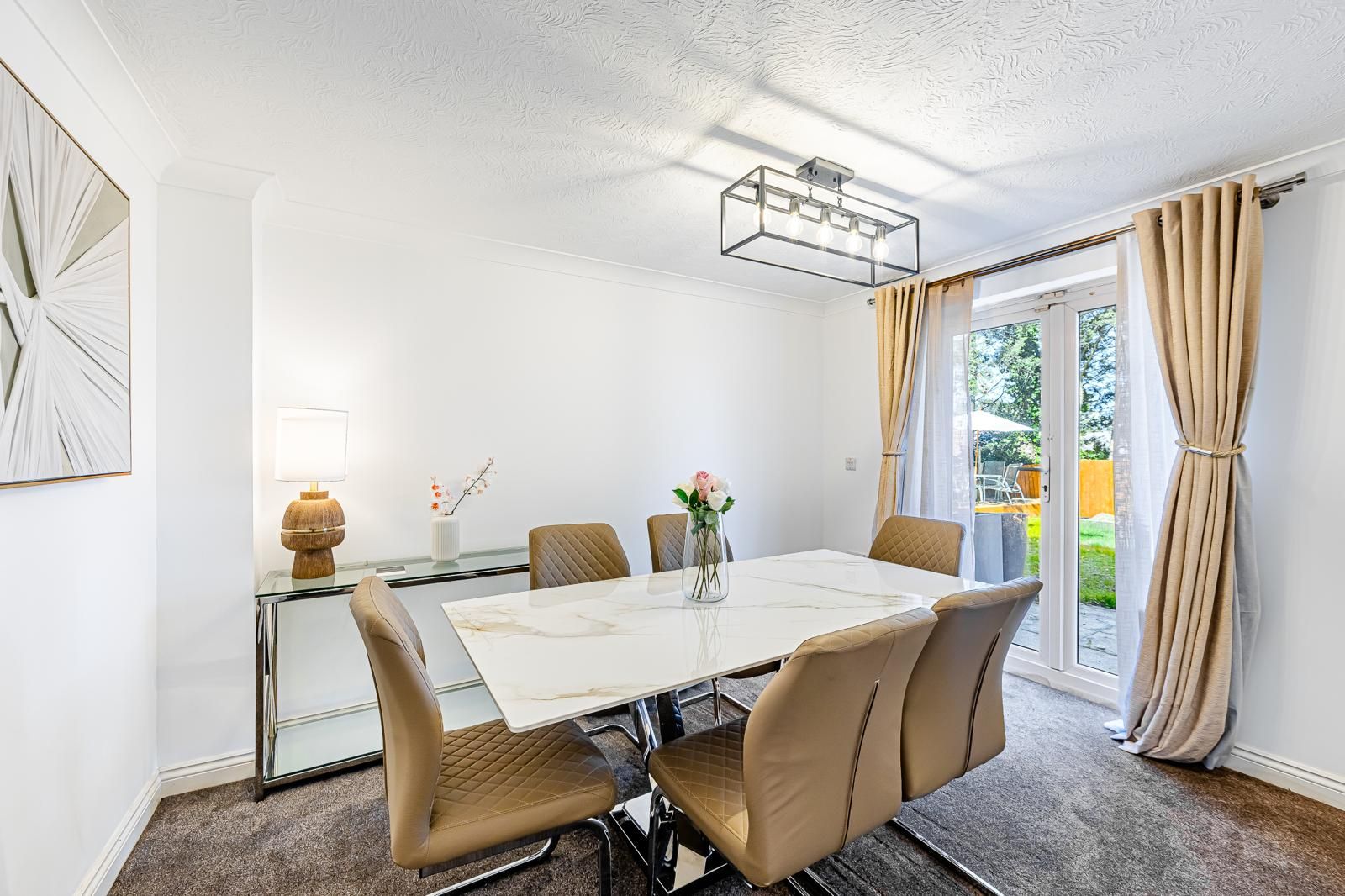 A dining area with a table and chairs, a vase with flowers, and a lamp.