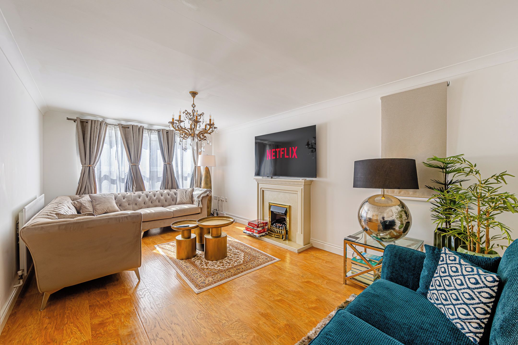 A living room with a sofa, a coffee table, a fireplace, a TV mounted on the wall, and a lamp.