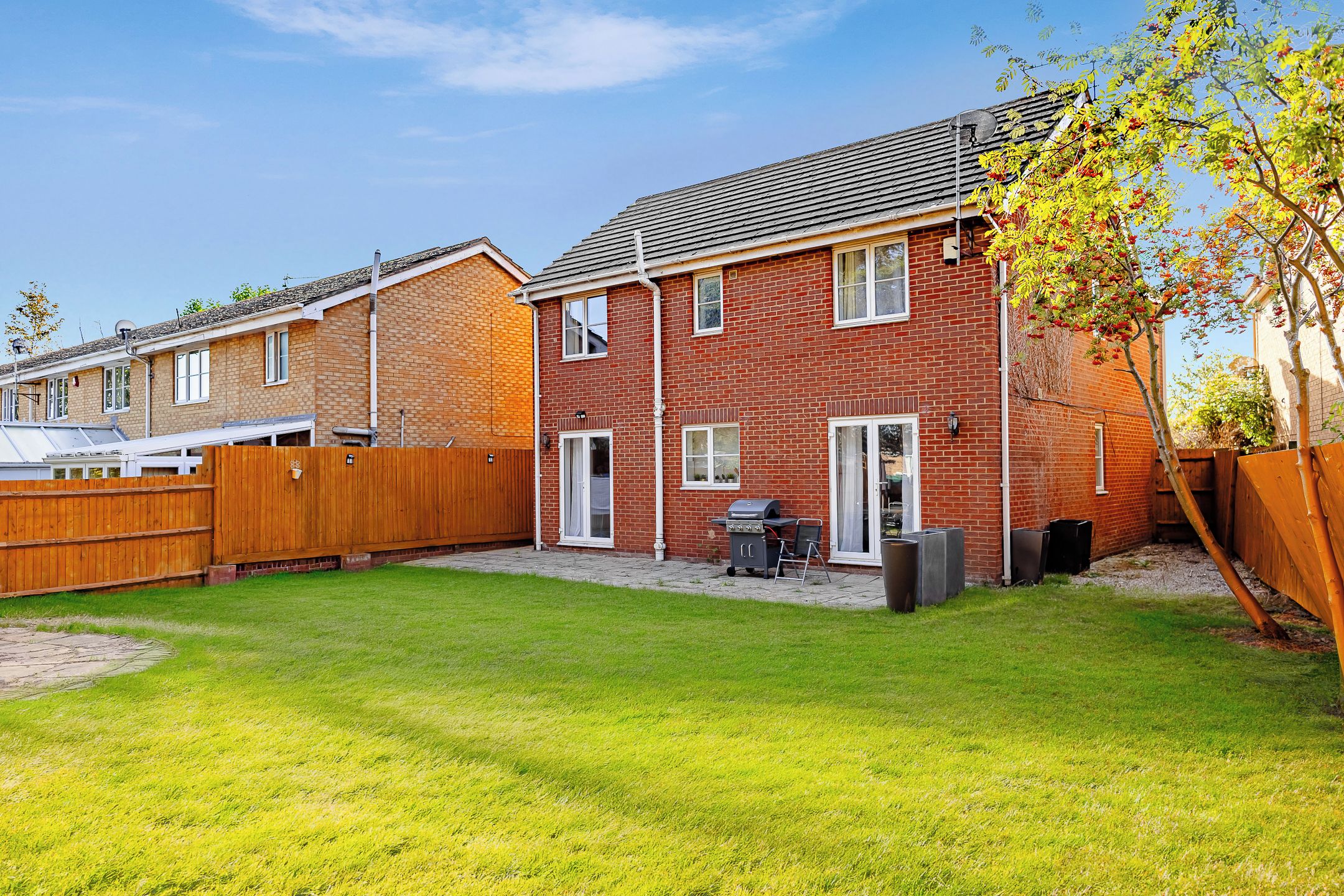 A residential property with a brick exterior, a wooden fence, and a well-maintained lawn.