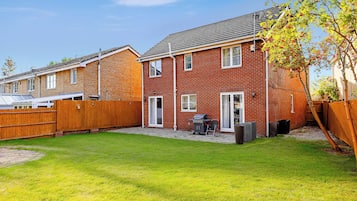 A residential property with a brick exterior, a wooden fence, and a well-maintained lawn.