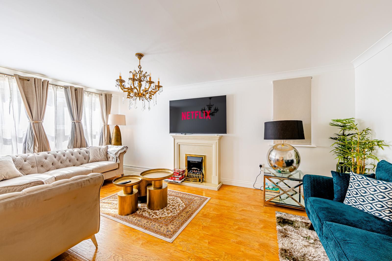 A living room with a sofa, a coffee table, a TV mounted on the wall, a fireplace, and a lamp.