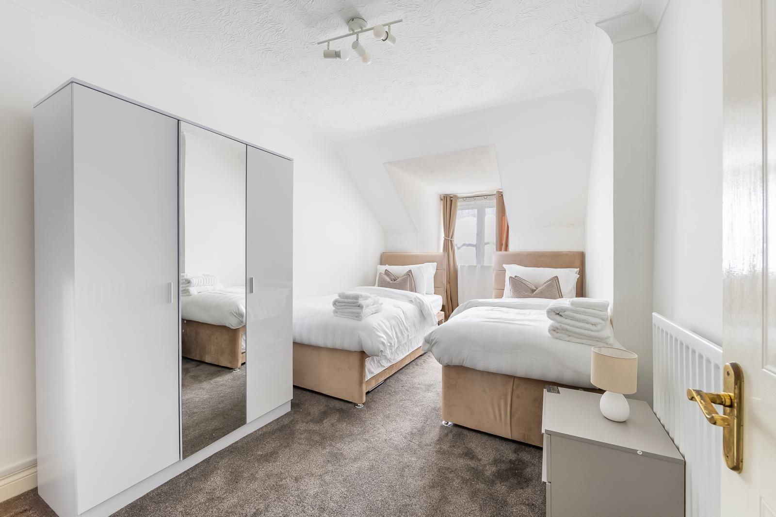 Une chambre avec deux lits, une armoire, une table de chevet et un radiateur.