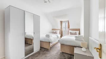A bedroom with two beds, a wardrobe, a bedside table, and a radiator.