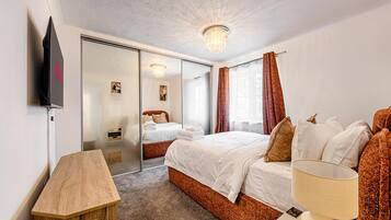 A hotel room with a bed, a desk, a lamp, a TV, and a sliding door leading to a bathroom.