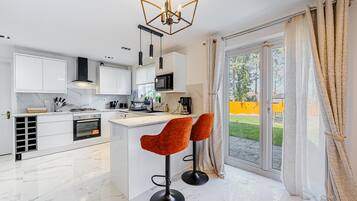 A modern kitchen with white cabinetry, a central island, and two bar stools.