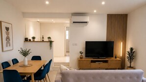 A modern living room with a sofa, TV, dining table, chairs, and a kitchen area in the background. - Charming house in the heart of the village with 3 private suites (Cintegabelle)