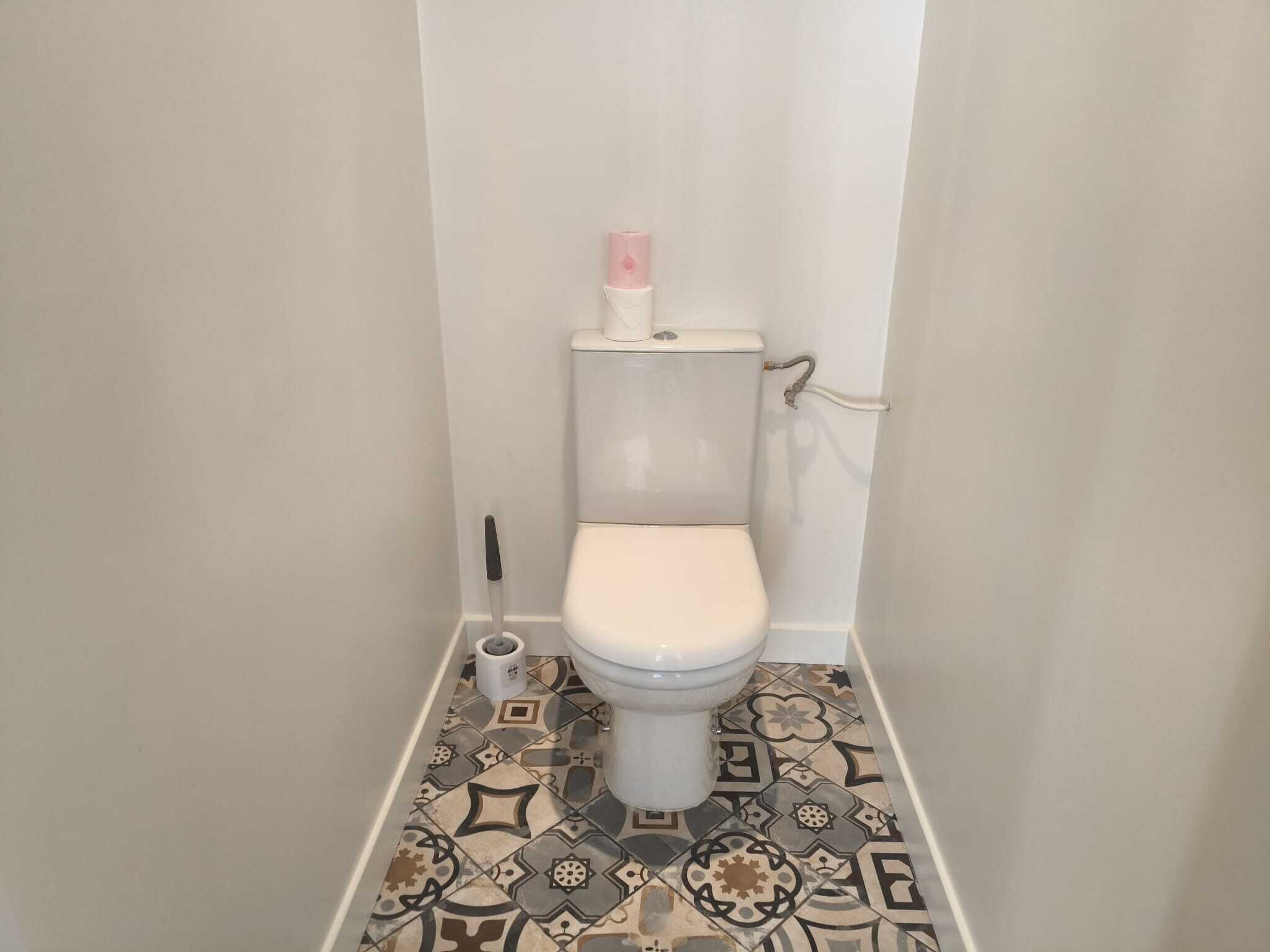 Toilet in een badkamer met vloertegels met patroon.