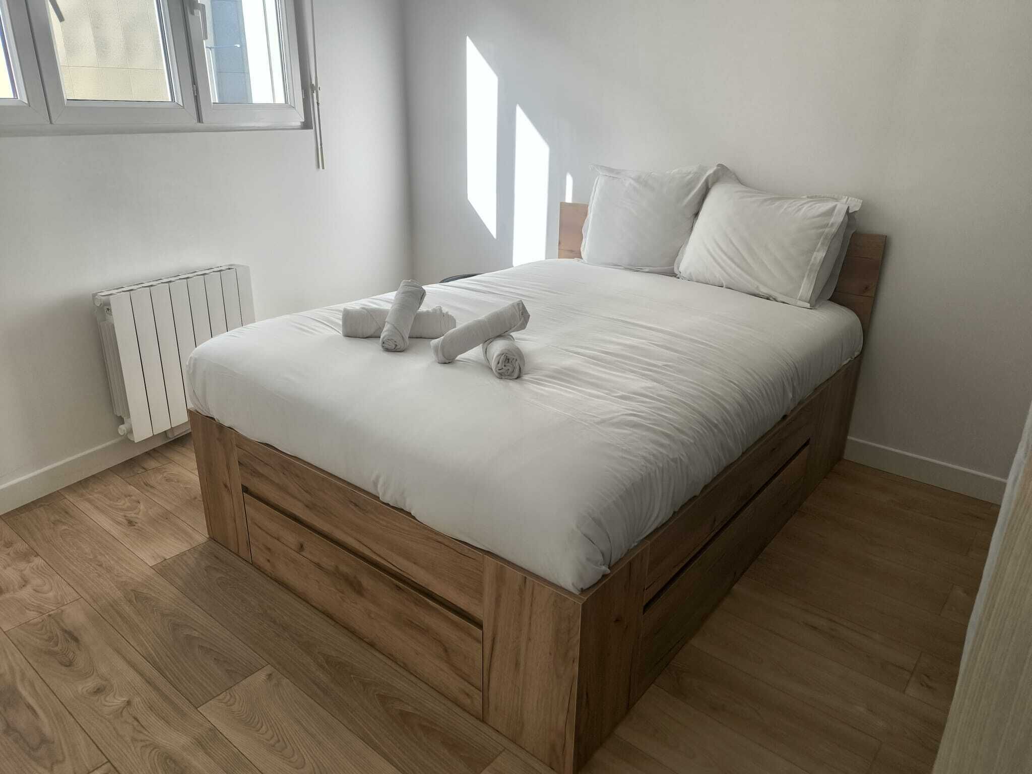 A bedroom with a wooden bed frame, white bedding, and a radiator.
