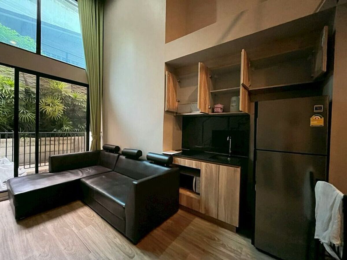 A modern kitchen with a built-in oven, a refrigerator, and wooden cabinets.