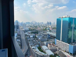 A cityscape with a prominent blue building, a highway, and a train track.