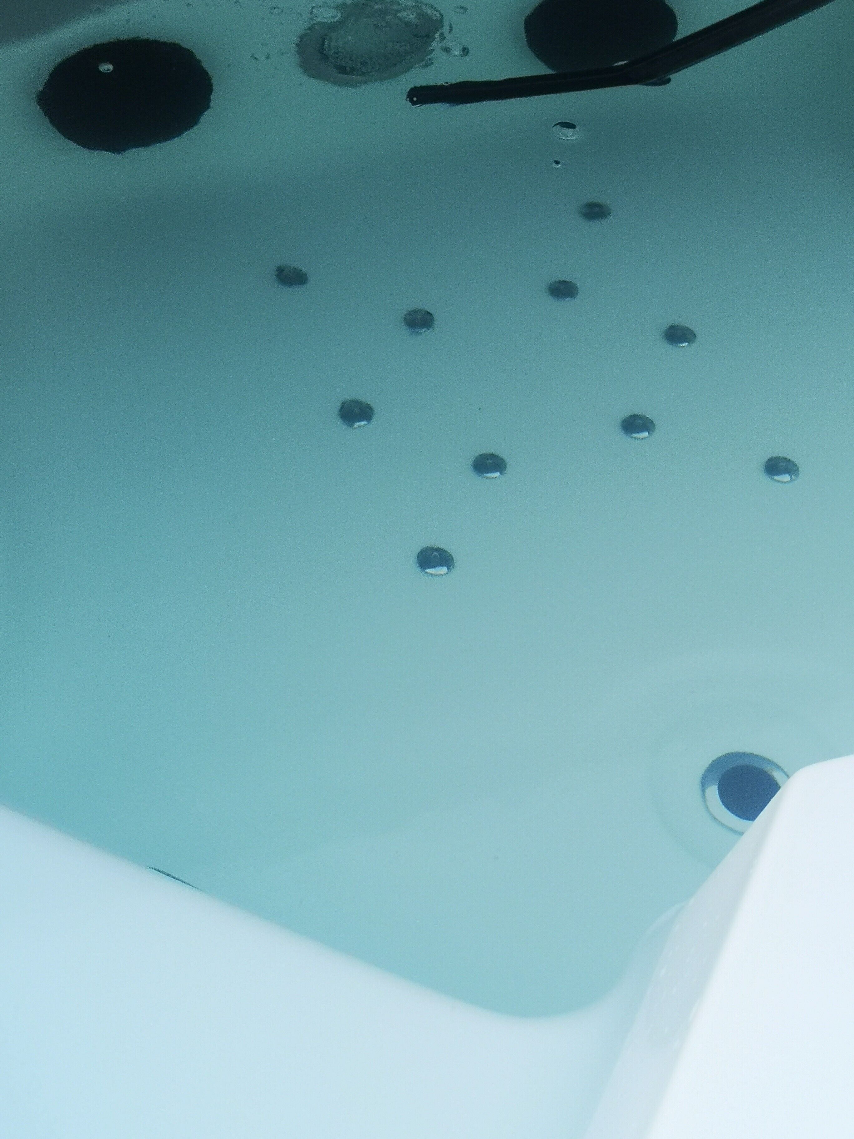 Une baignoire avec un drain, un robinet et plusieurs bulles.