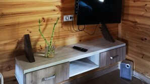 Ein Holzblockhaus-Interieur mit an der Wand montiertem Fernseher, einer Holz-Unterhaltungseinrichtung darunter und mehreren gerahmten Kunstwerken.