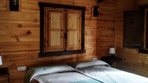 Eine Holzhütte mit zwei Betten und einem Fenster mit Aussicht.