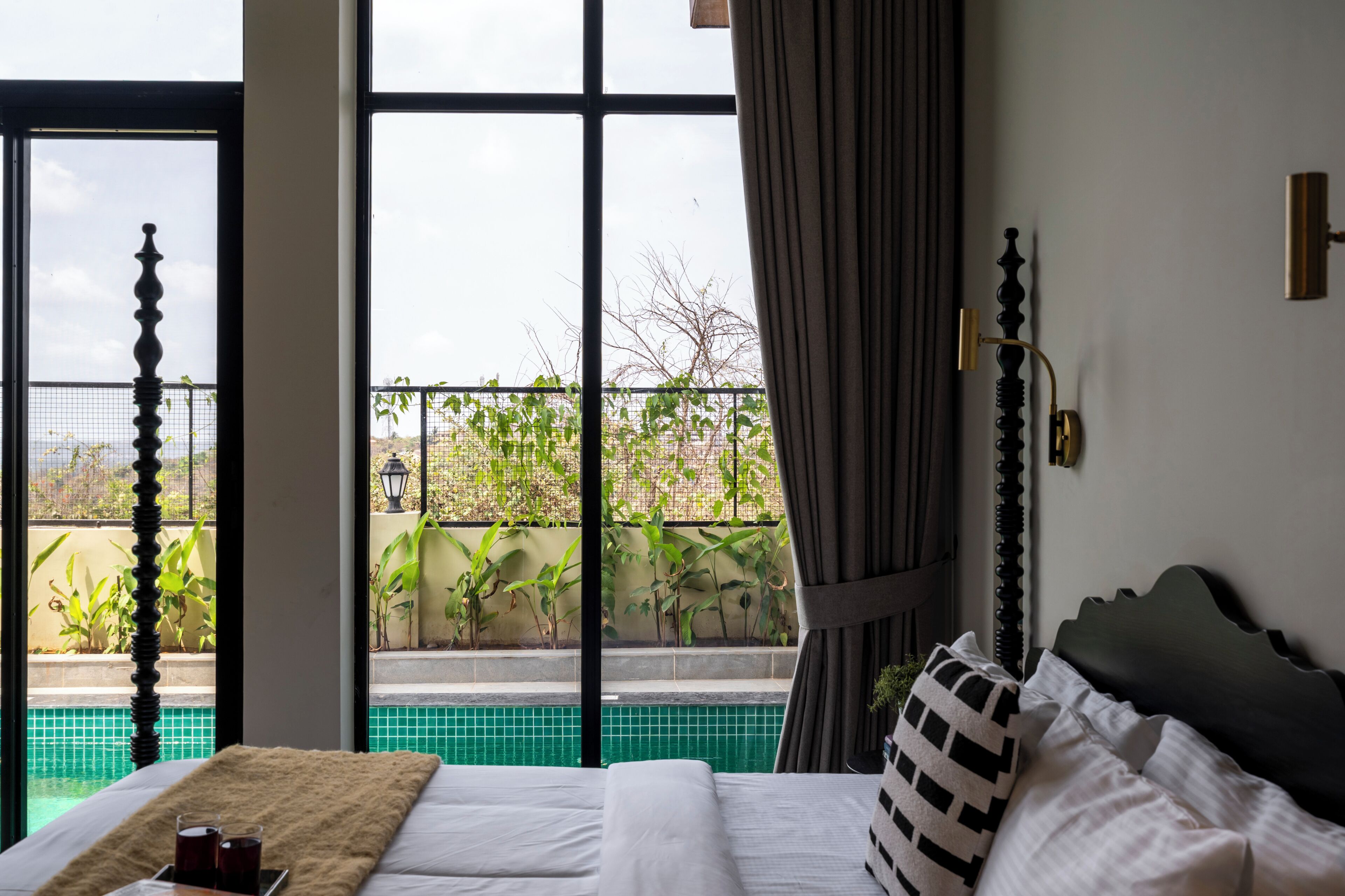 Une chambre avec un lit, une vue sur une piscine et un balcon agrémenté de plantes.